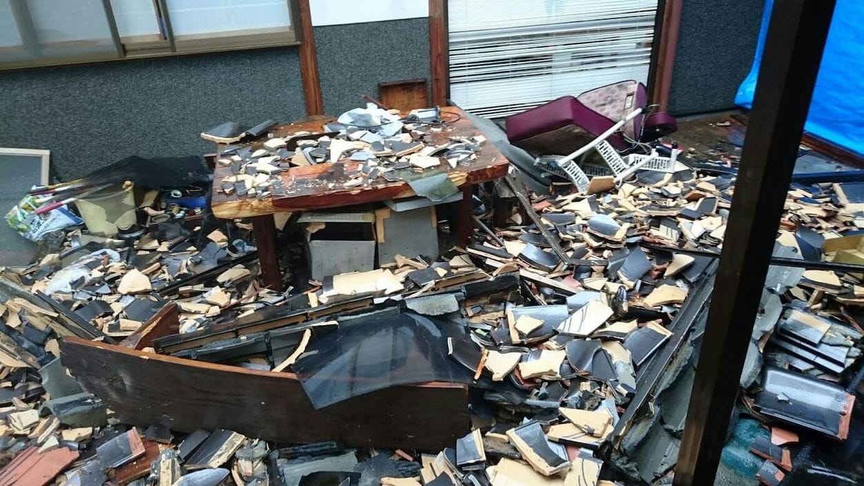 割れた瓦など災害ごみが散乱する被災住宅の庭